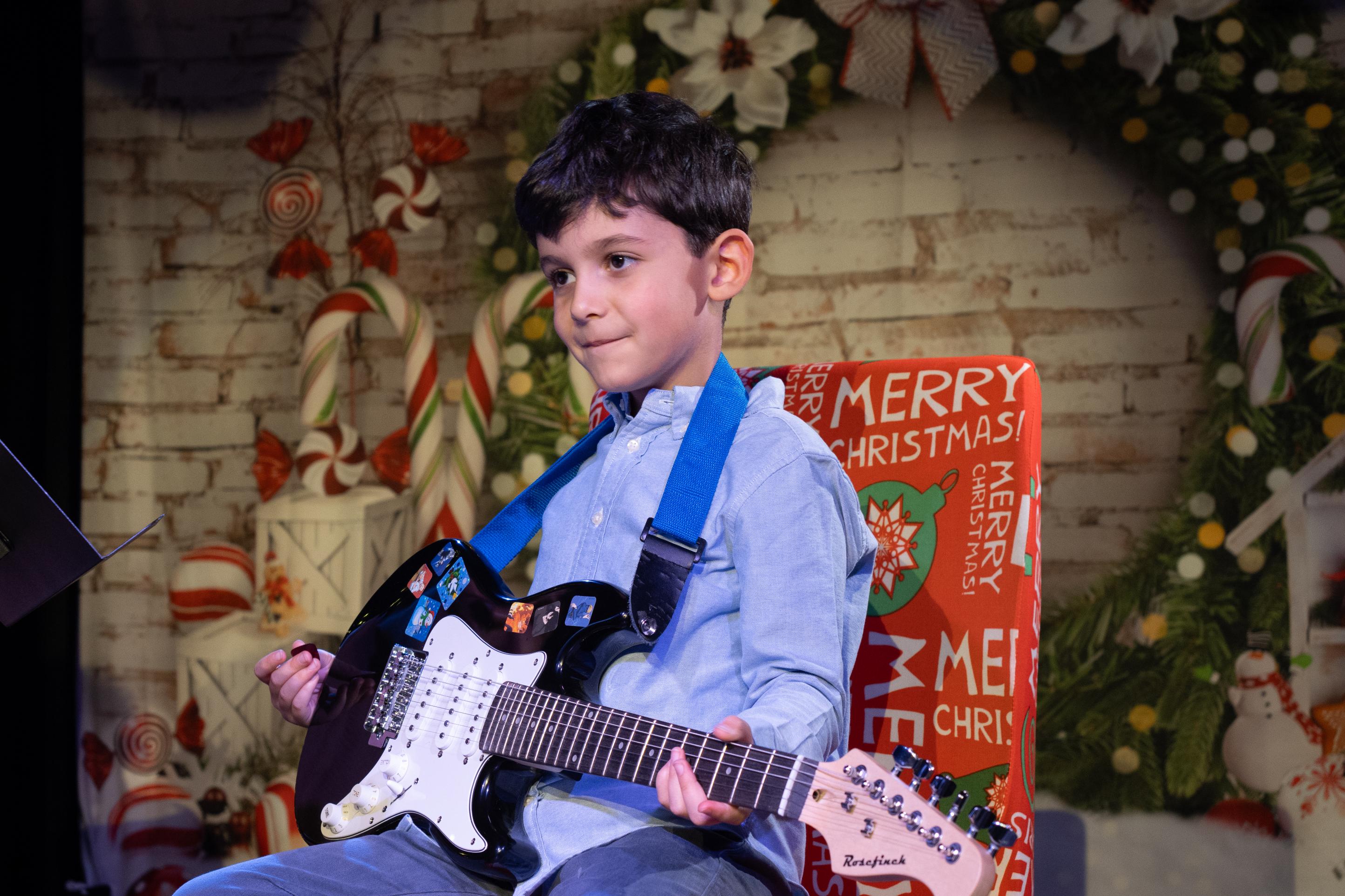 Child guitarist strumming during a christmas musical